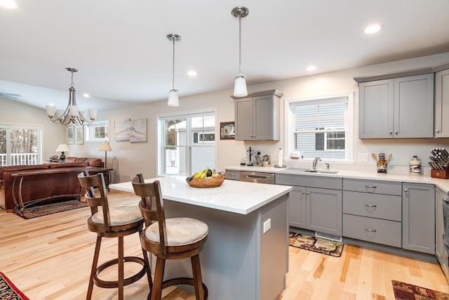 kitchen with pendant lighting, sink, gray cabinets, light hardwood / wood-style flooring, and a kitchen island