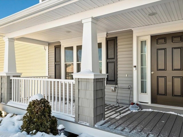 snow covered property entrance with covered porch