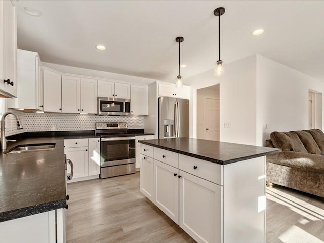 kitchen featuring sink, decorative light fixtures, a center island, appliances with stainless steel finishes, and white cabinets