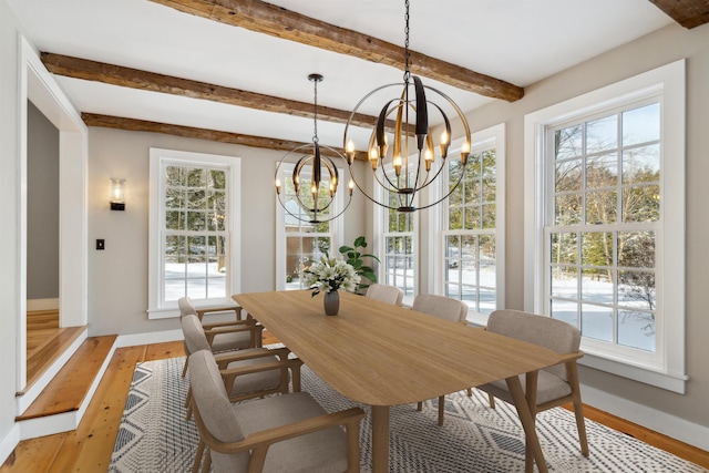 dining space featuring beamed ceiling, a chandelier, and light hardwood / wood-style floors