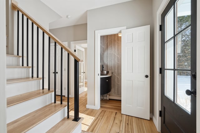 foyer with baseboard heating and light hardwood / wood-style flooring