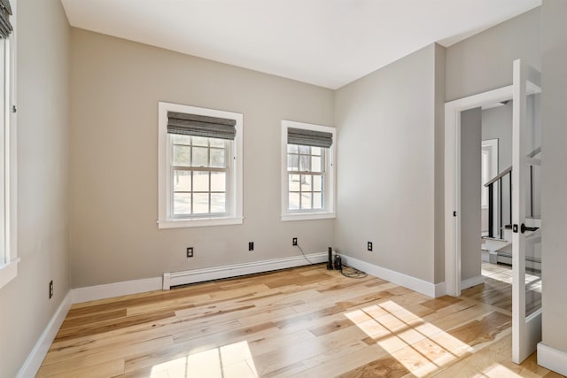 empty room featuring baseboard heating and light hardwood / wood-style flooring