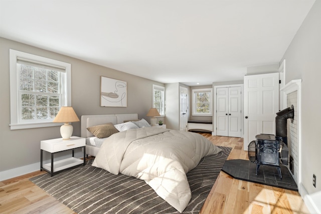 bedroom featuring a wood stove, a closet, and light wood-type flooring