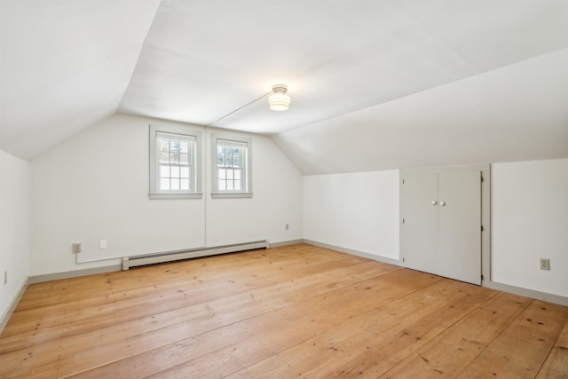 additional living space featuring baseboard heating, lofted ceiling, and light hardwood / wood-style flooring