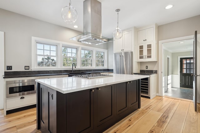 kitchen featuring white cabinetry, island range hood, stainless steel appliances, and decorative light fixtures