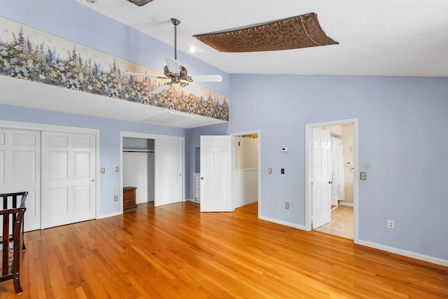 bedroom with lofted ceiling, light hardwood / wood-style flooring, and two closets