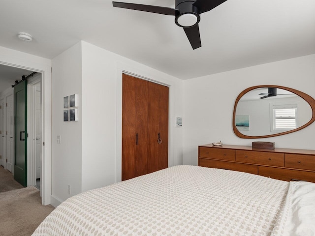 carpeted bedroom featuring ceiling fan and a barn door