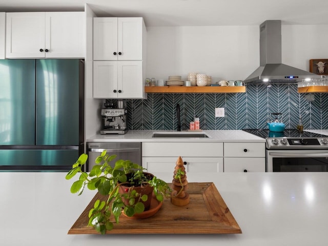 kitchen with sink, white cabinetry, stainless steel appliances, decorative backsplash, and wall chimney exhaust hood