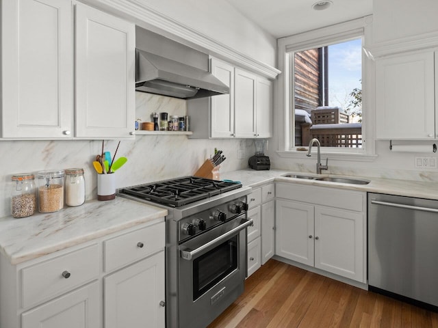 kitchen with white cabinetry, wall chimney range hood, stainless steel appliances, and sink