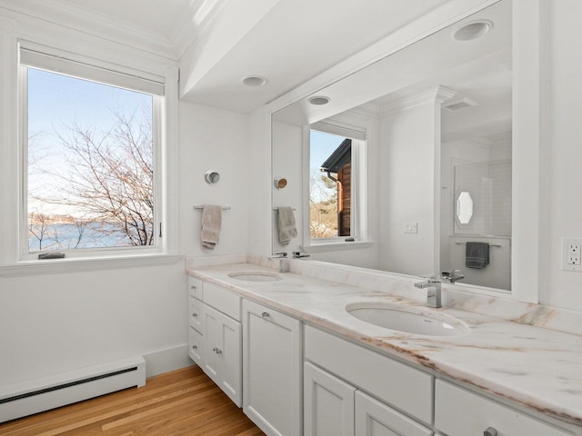 bathroom featuring vanity, a baseboard heating unit, hardwood / wood-style floors, and crown molding