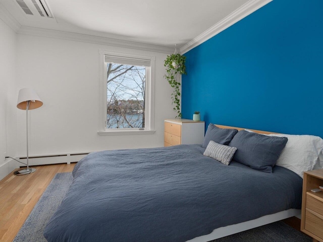 bedroom featuring a baseboard heating unit, ornamental molding, and light wood-type flooring