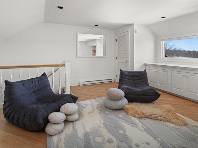 living area with lofted ceiling, a baseboard heating unit, and light hardwood / wood-style flooring