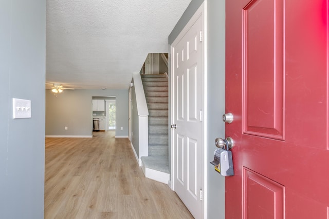 foyer entrance with ceiling fan, a textured ceiling, and light hardwood / wood-style floors