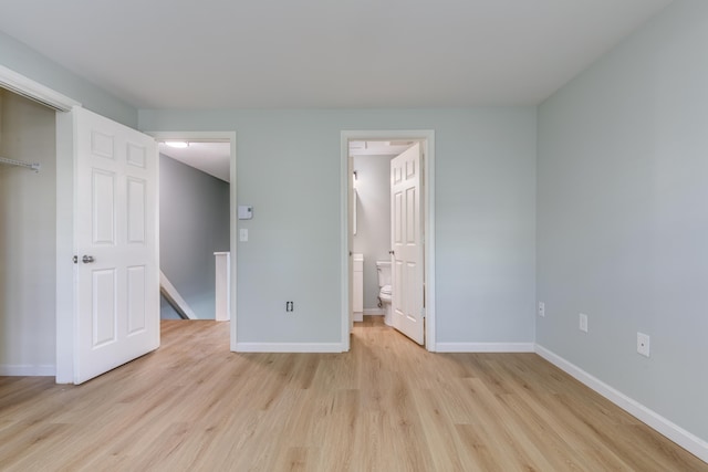 unfurnished bedroom featuring ensuite bathroom and light wood-type flooring