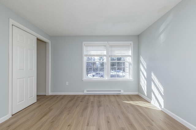 unfurnished bedroom featuring baseboard heating and light hardwood / wood-style floors