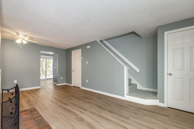 unfurnished living room with ceiling fan, a textured ceiling, and light wood-type flooring