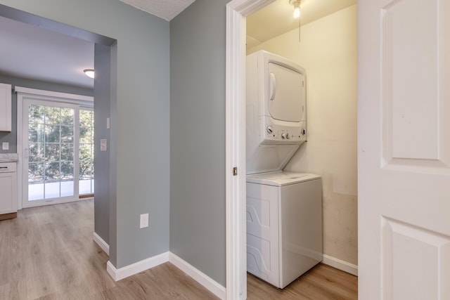 laundry room with stacked washer and clothes dryer and light hardwood / wood-style flooring