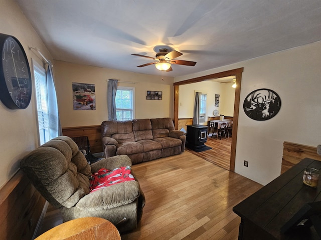 living room featuring hardwood / wood-style flooring, ceiling fan, and a wood stove