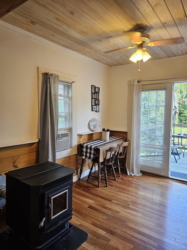 dining room featuring wood ceiling, a wealth of natural light, wood-type flooring, and a wood stove