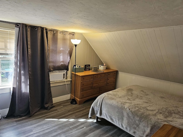 bedroom with wooden walls, lofted ceiling, cooling unit, dark hardwood / wood-style flooring, and a textured ceiling