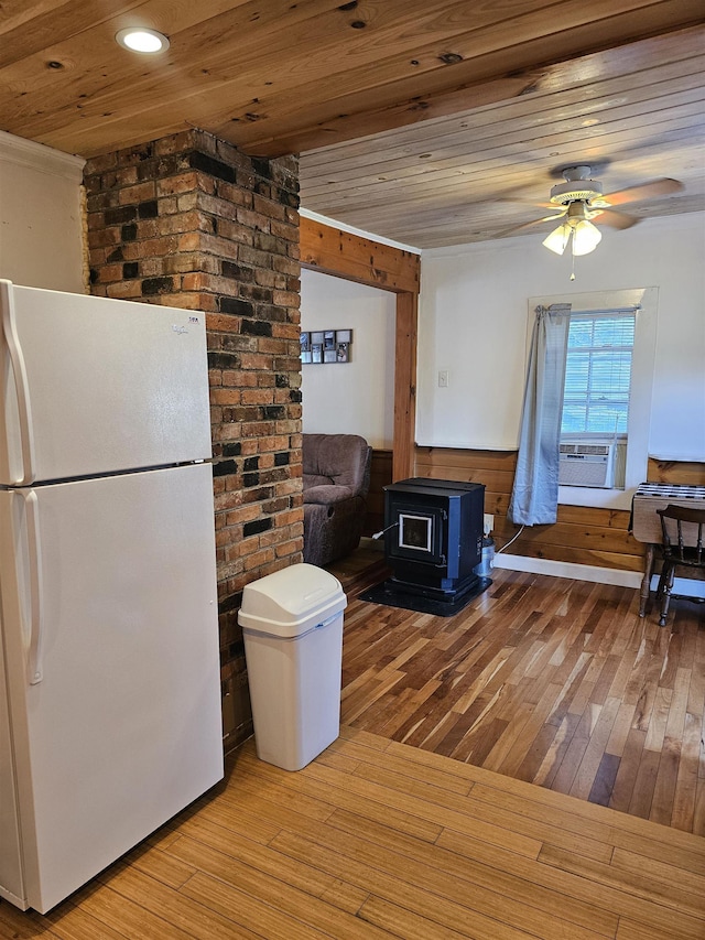 kitchen featuring wooden ceiling, a wood stove, white fridge, ceiling fan, and light hardwood / wood-style floors