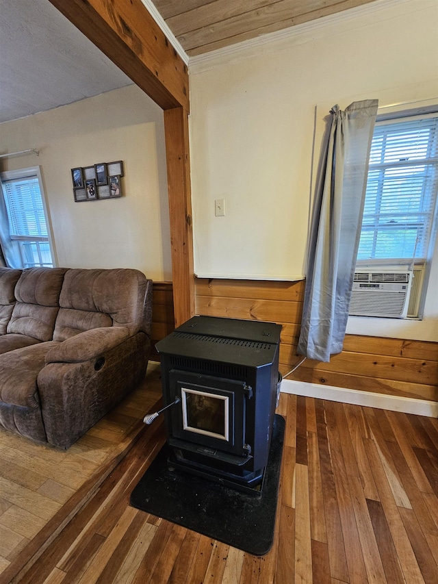 living room with a wealth of natural light, a wood stove, cooling unit, crown molding, and dark wood-type flooring