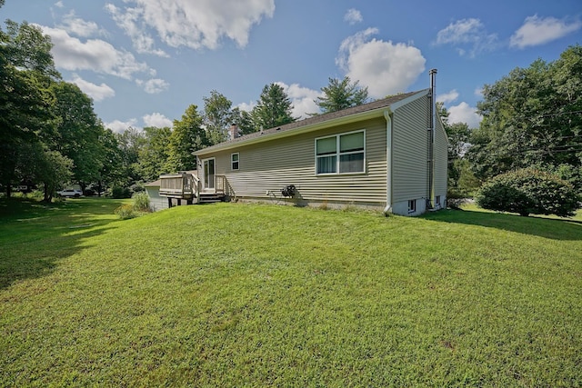 rear view of house with a wooden deck and a lawn