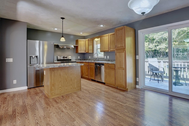 kitchen featuring sink, appliances with stainless steel finishes, a center island, decorative light fixtures, and light wood-type flooring