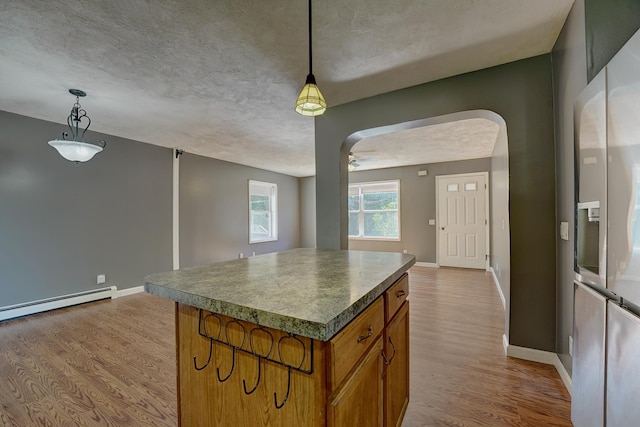 kitchen featuring pendant lighting, a center island, light hardwood / wood-style flooring, and stainless steel refrigerator with ice dispenser