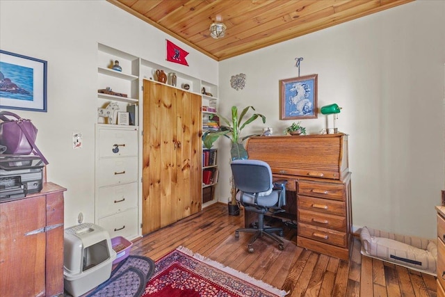 office space with built in shelves, light hardwood / wood-style floors, and wooden ceiling