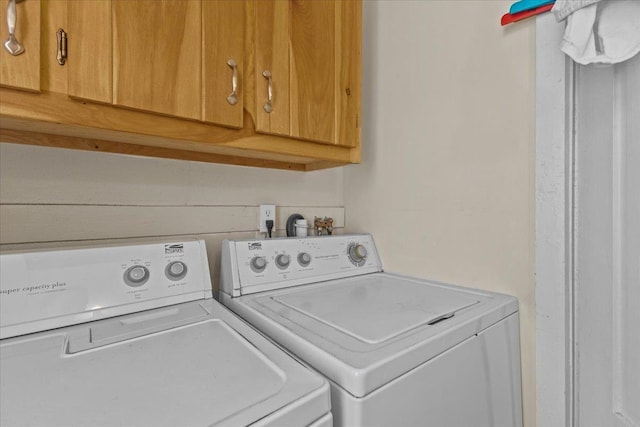 clothes washing area featuring cabinets and separate washer and dryer