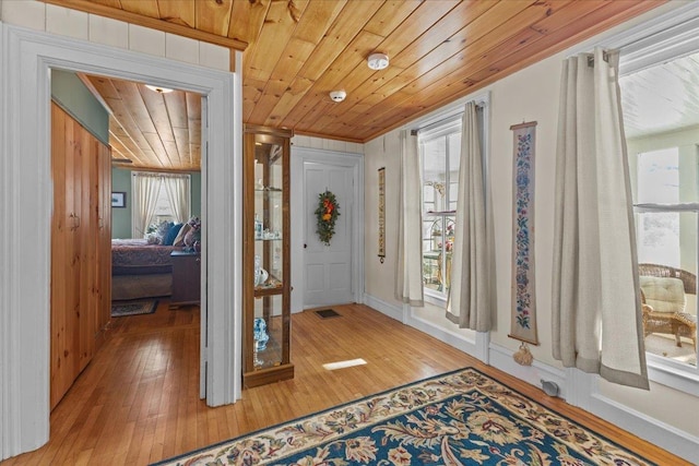 foyer entrance with wood ceiling, a healthy amount of sunlight, and wood-type flooring