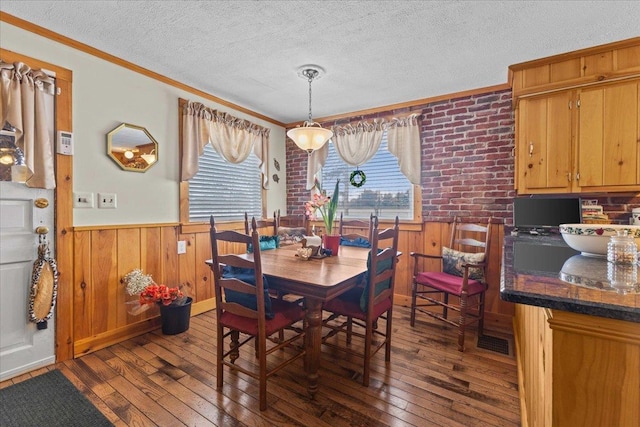 dining space featuring ornamental molding, dark hardwood / wood-style floors, a textured ceiling, and wood walls