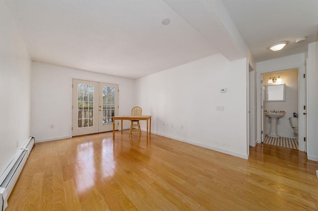 empty room with a baseboard radiator, french doors, and light wood-type flooring