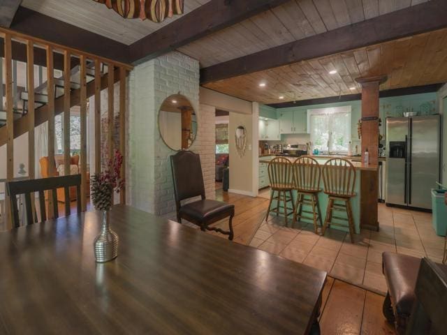 tiled dining space featuring beam ceiling and wooden ceiling