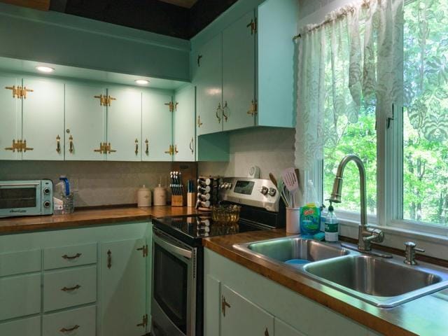 kitchen featuring tasteful backsplash, white cabinetry, sink, and electric range