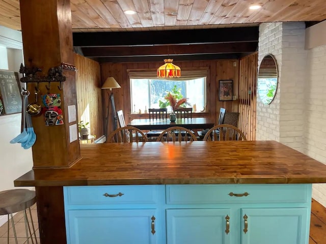 kitchen with wood ceiling, wooden counters, wooden walls, beamed ceiling, and brick wall