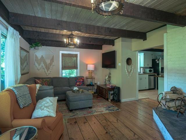 living room with beamed ceiling, a chandelier, hardwood / wood-style floors, and wood ceiling