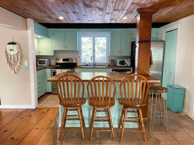 kitchen with wood ceiling, stainless steel appliances, sink, and ornate columns