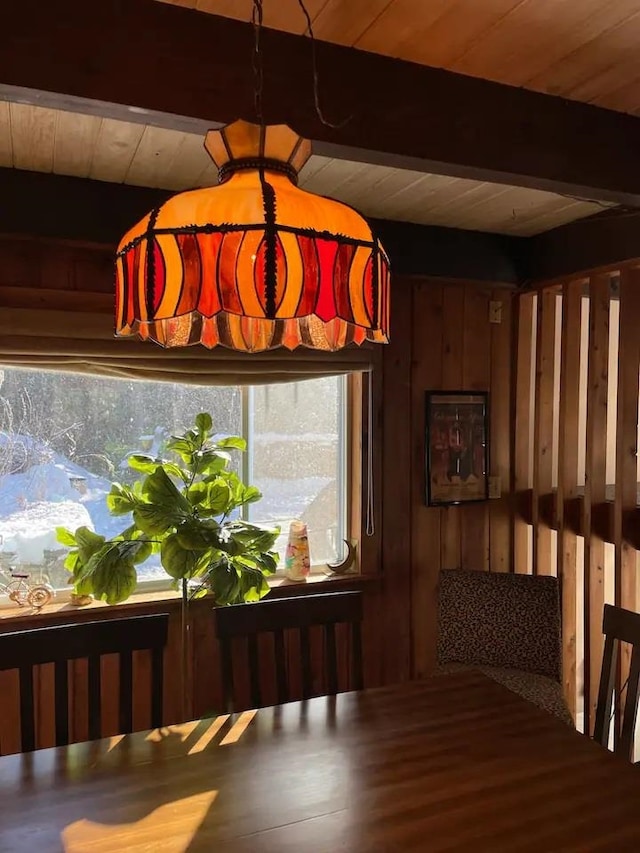 dining space with wooden ceiling, beam ceiling, and wood walls