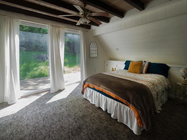 bedroom with lofted ceiling with beams, access to exterior, and carpet floors