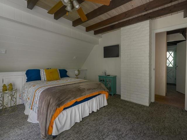 bedroom with ceiling fan, vaulted ceiling with beams, and dark carpet