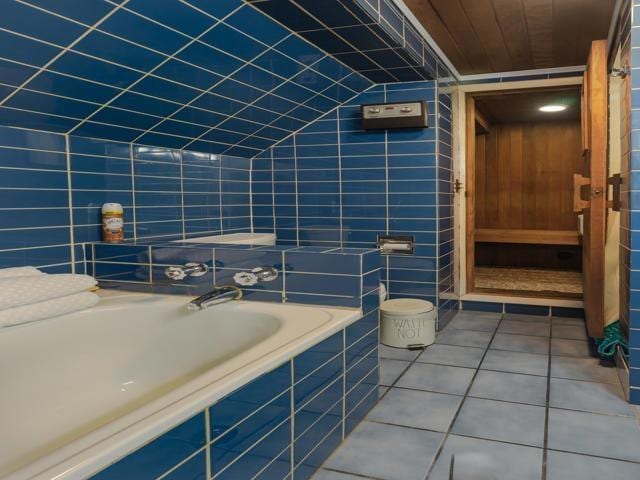 bathroom featuring tiled bath, tile patterned flooring, and tile walls