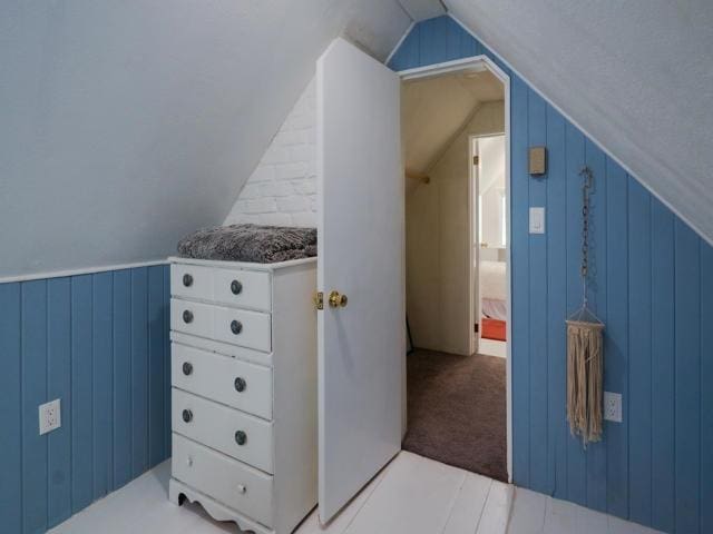 additional living space with lofted ceiling and wooden walls