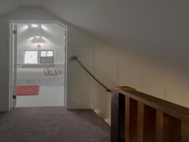 corridor with lofted ceiling and carpet floors