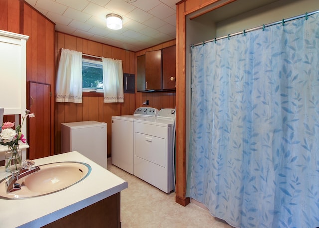 bathroom featuring washing machine and clothes dryer, vanity, and wood walls