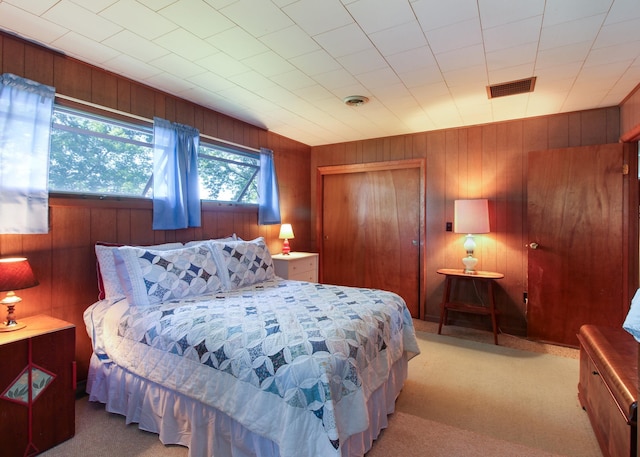 carpeted bedroom featuring wooden walls and a closet