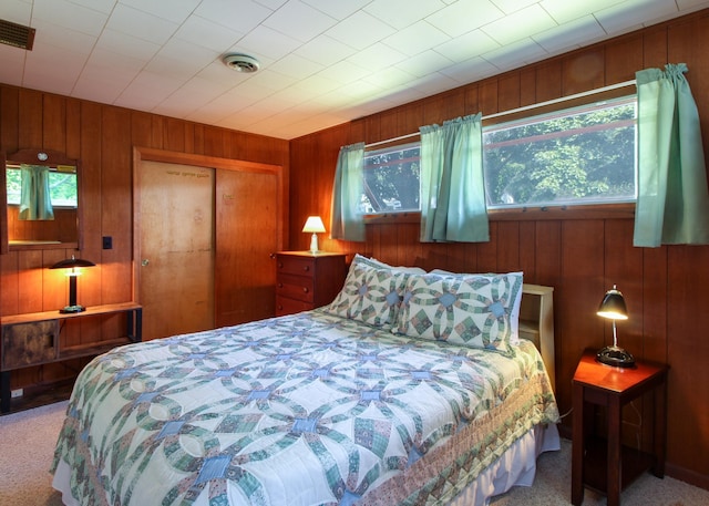 bedroom with carpet flooring, a closet, and wood walls