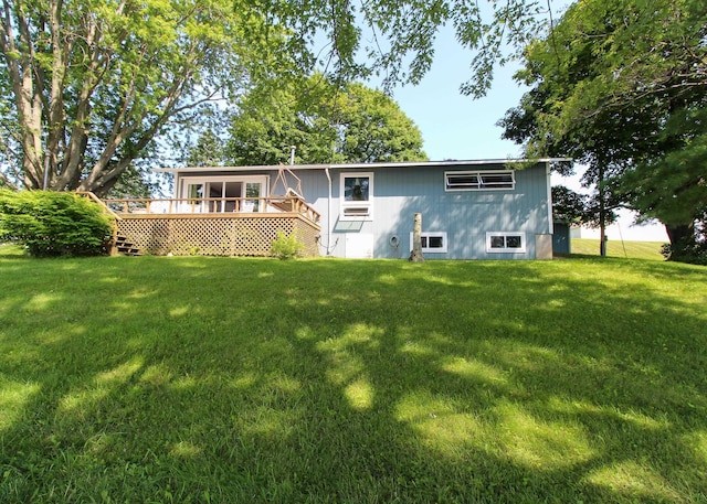 rear view of property with a wooden deck and a lawn