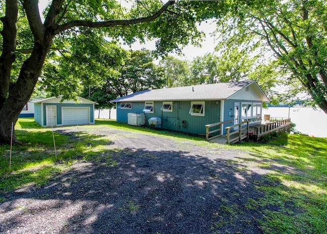 view of front of home featuring a garage, a wooden deck, and an outbuilding